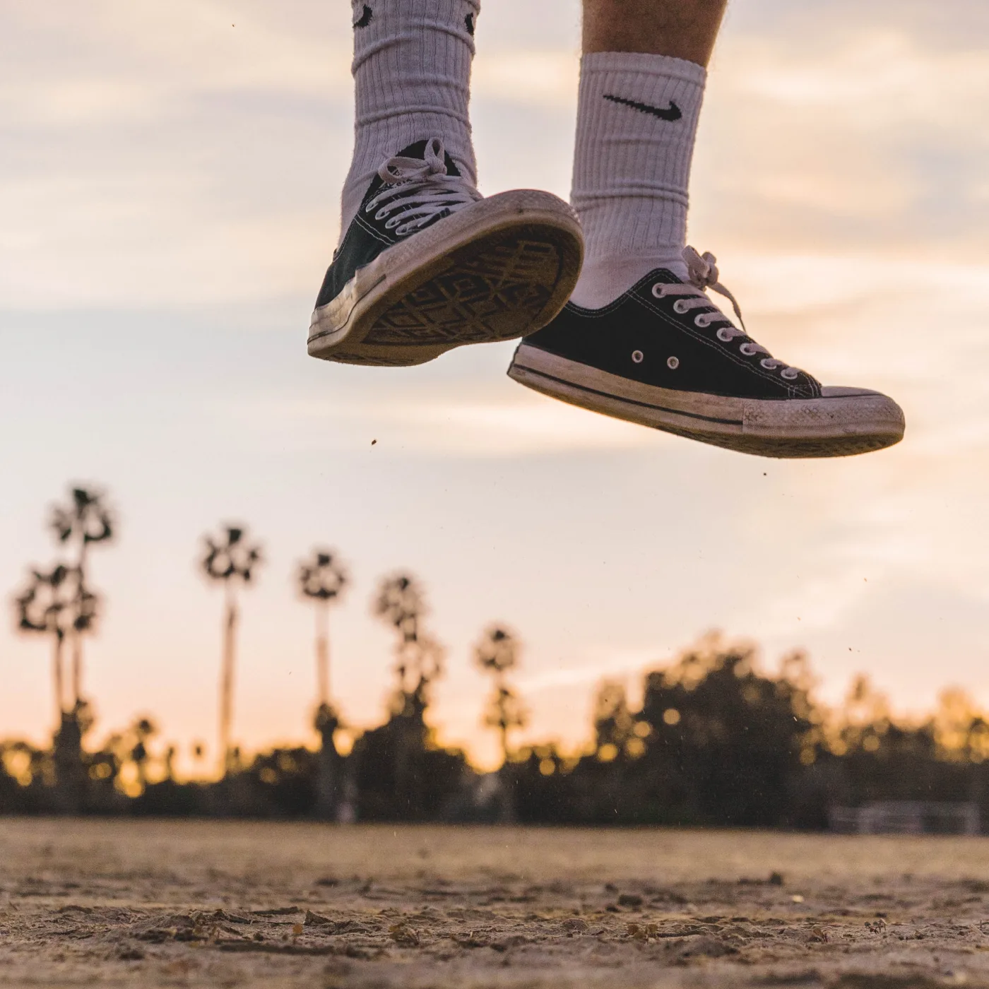 An athlete's sneakers floating off the ground mid-jump at sunset